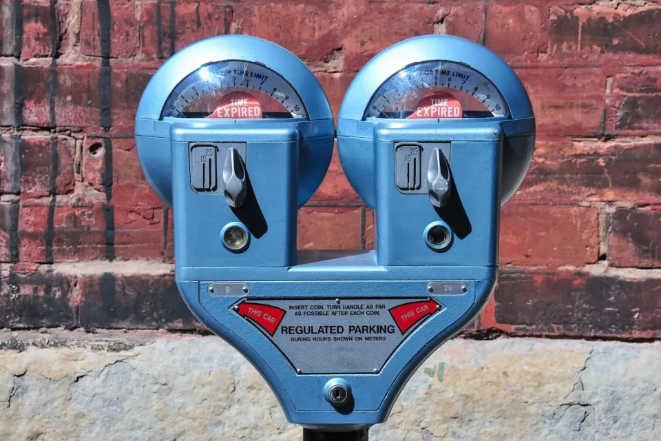 Close-up of old-fashioned blue double parking meter against red brick wall.
